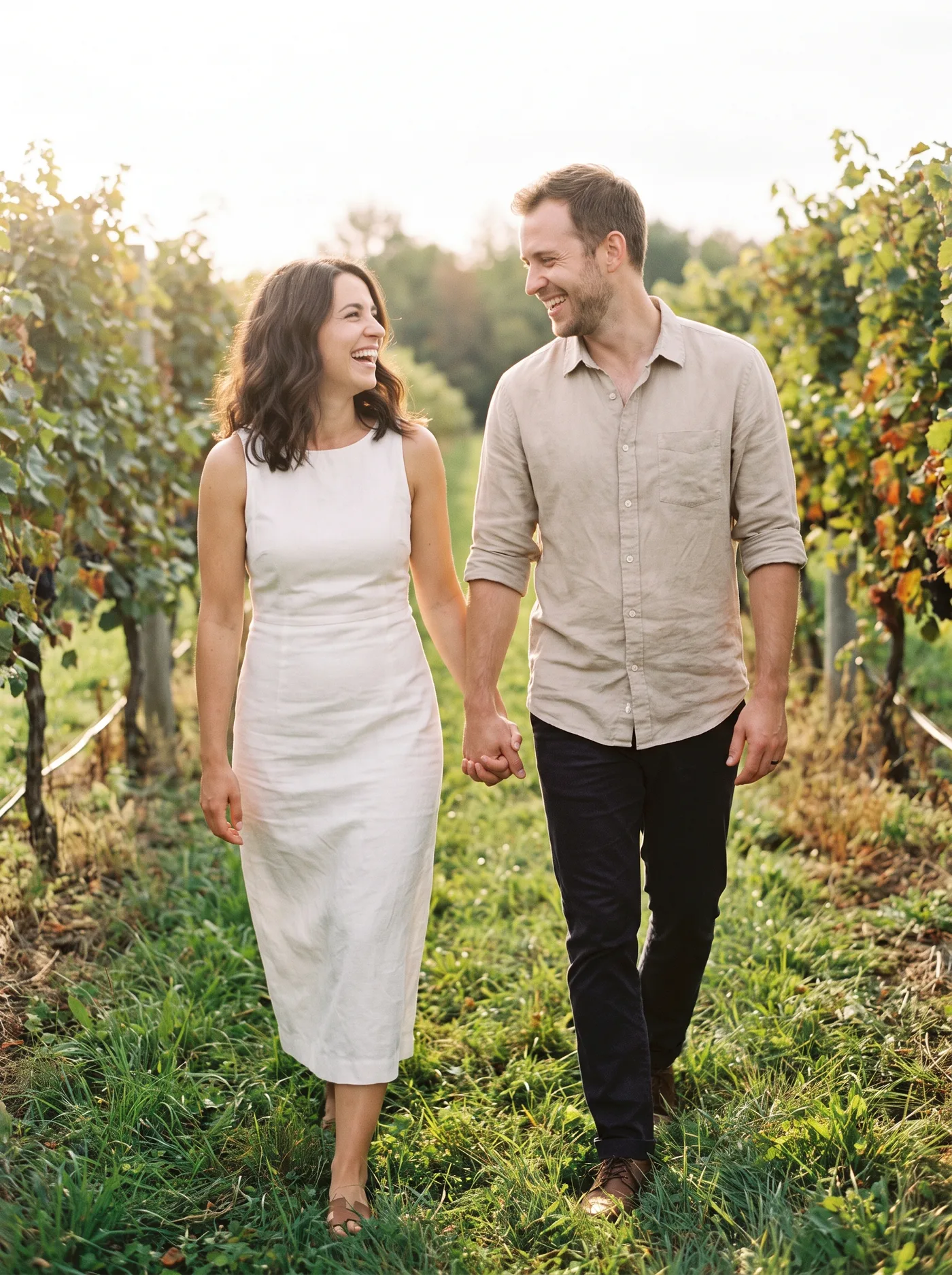 Maria et Mike, riant en marchant main dans la main dans un vignoble